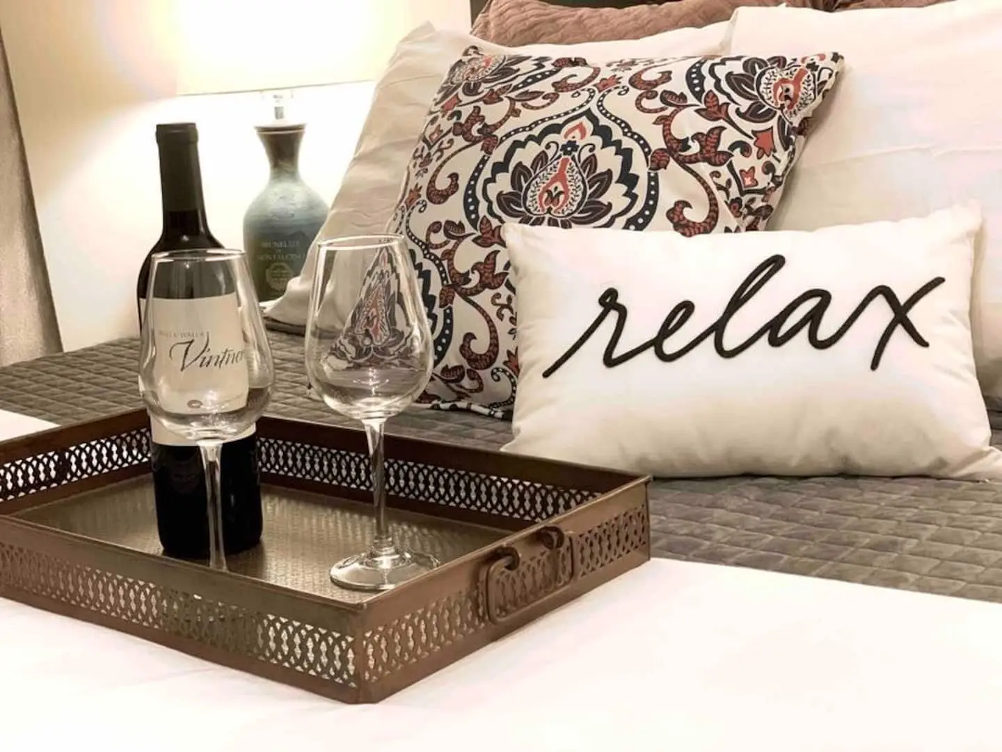 Welcome tray with wine glasses and a “relax” pillow on the bed at Magnolia House in Bend