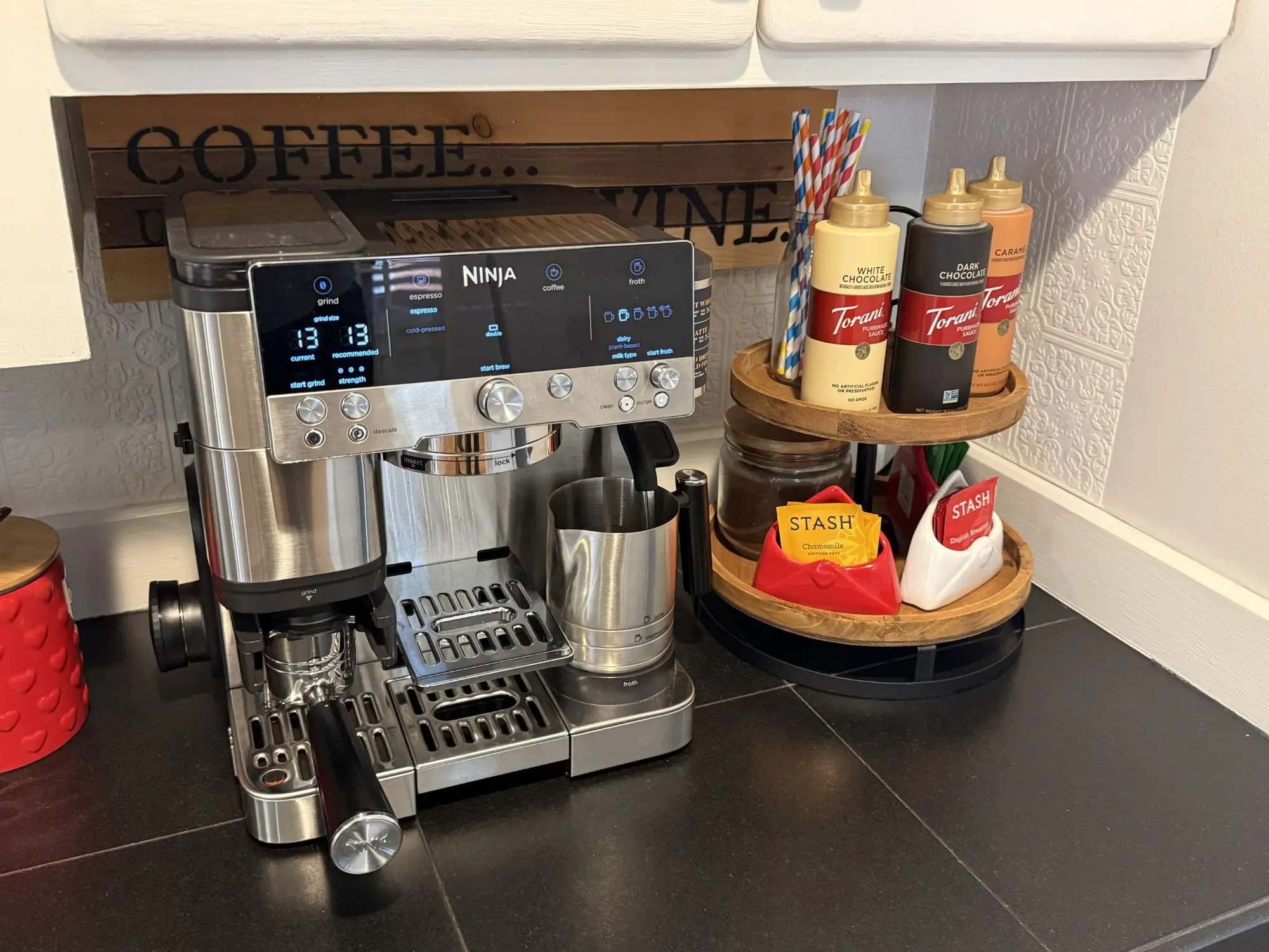 Espresso machine with grinder and milk frother beside flavored syrups and a tea station at the coffee bar in Magnolia House, Bend, Oregon