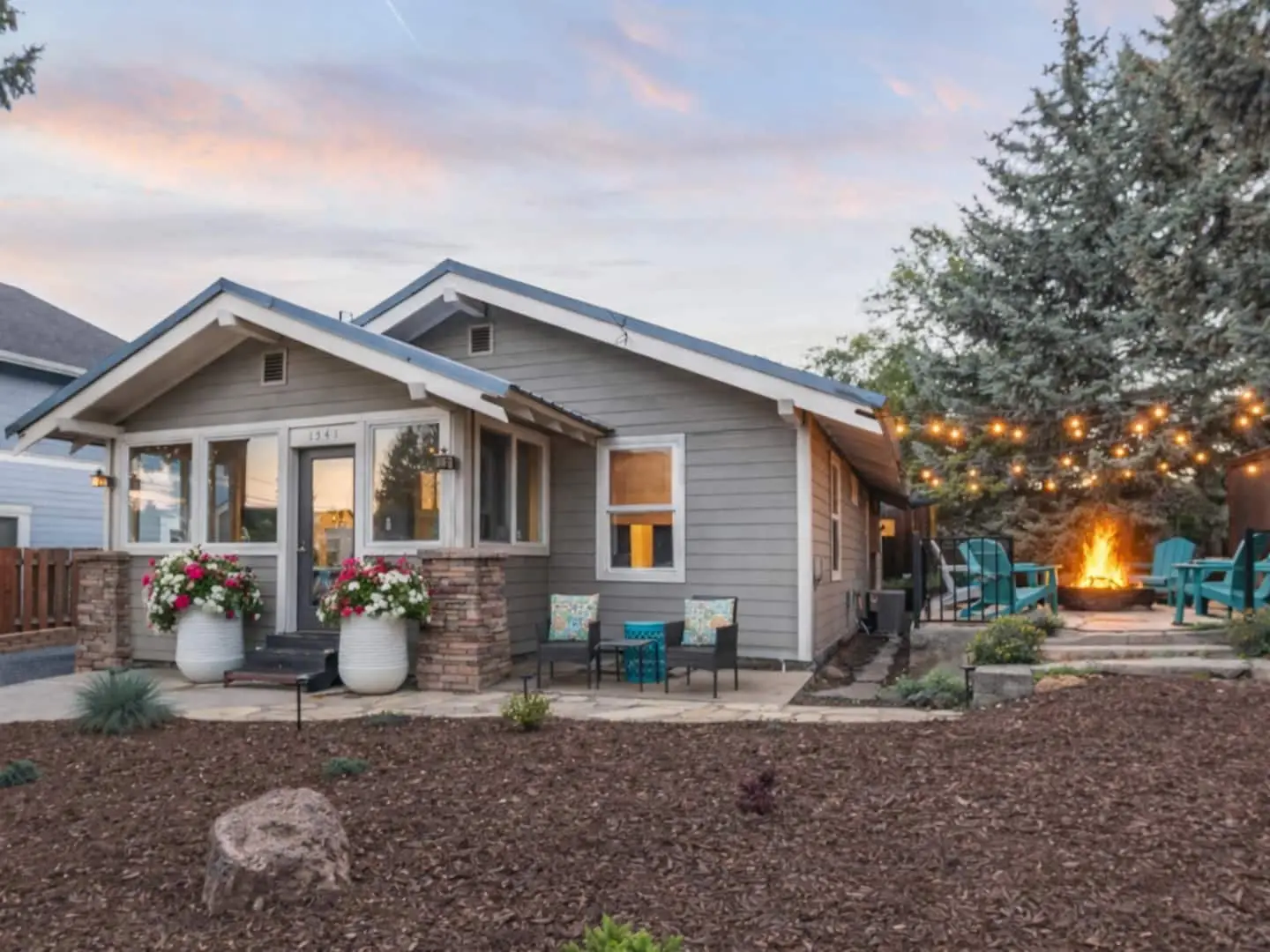 Magnolia House craftsman exterior at dusk in Bend, Oregon with warm porch lights and the backyard firepit glowing