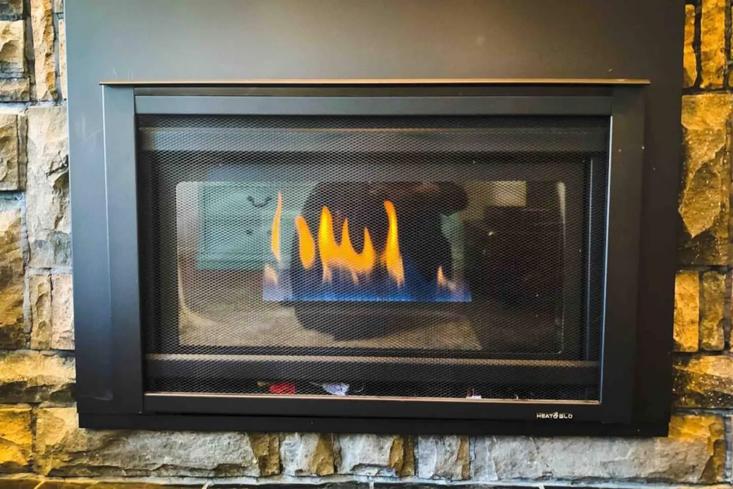 Gas fireplace flames glowing in the stone hearth at Magnolia House in Bend, Oregon