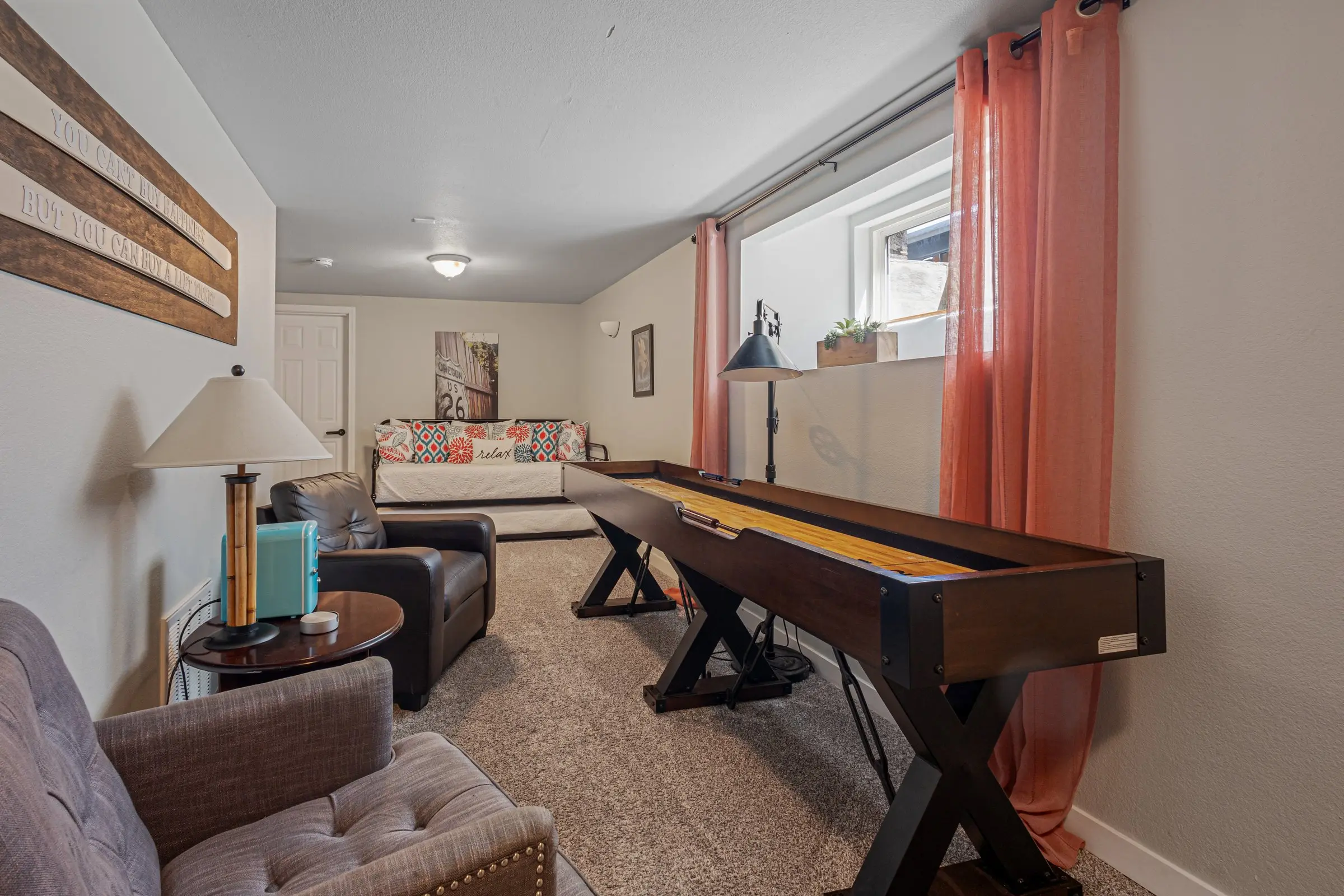 Lower-level game room with shuffleboard table and lounge seating at Magnolia House in Bend, Oregon
