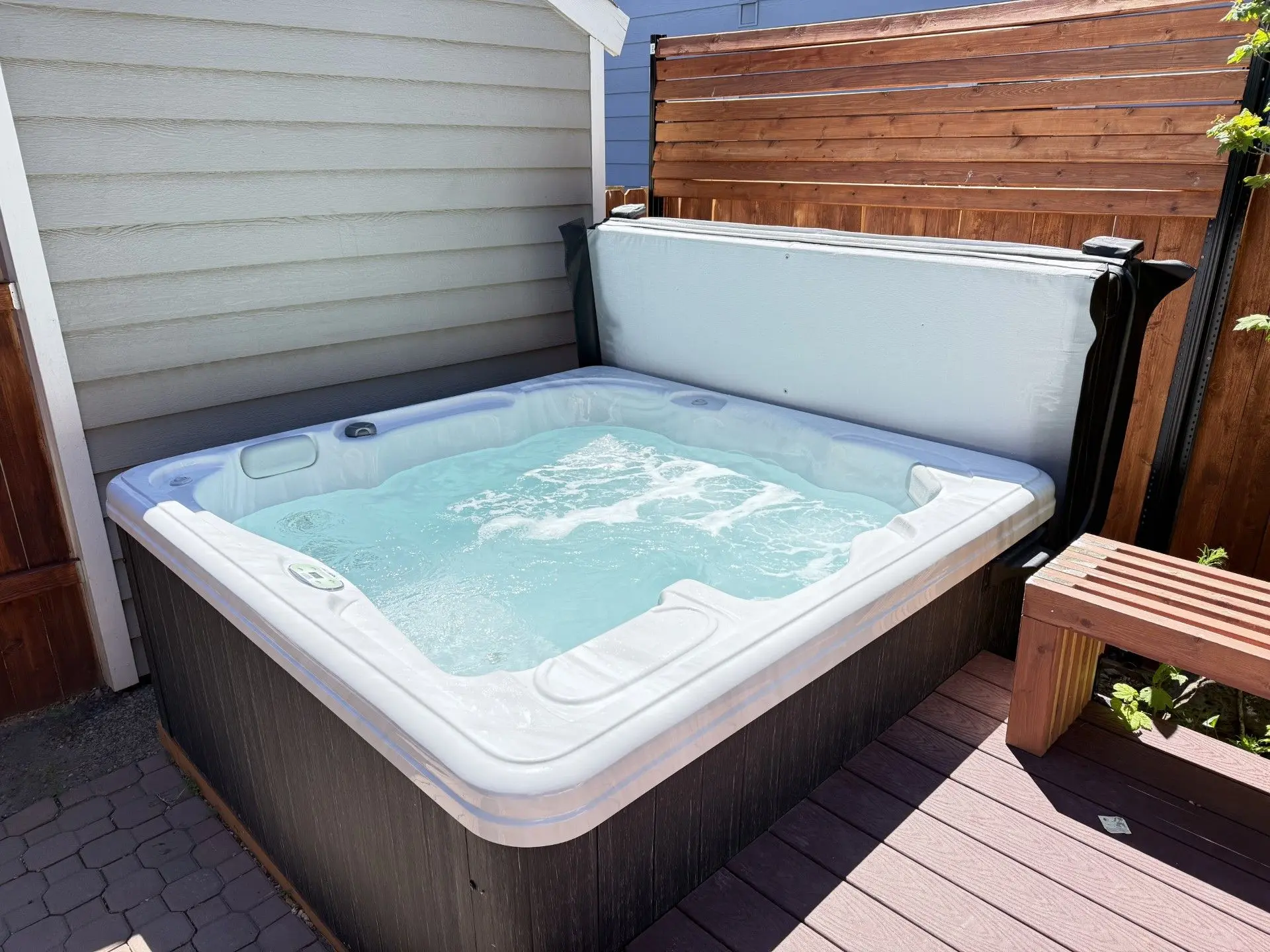 Private hot tub bubbling on the back deck at Magnolia House in Bend, Oregon, tucked behind a cedar privacy screen