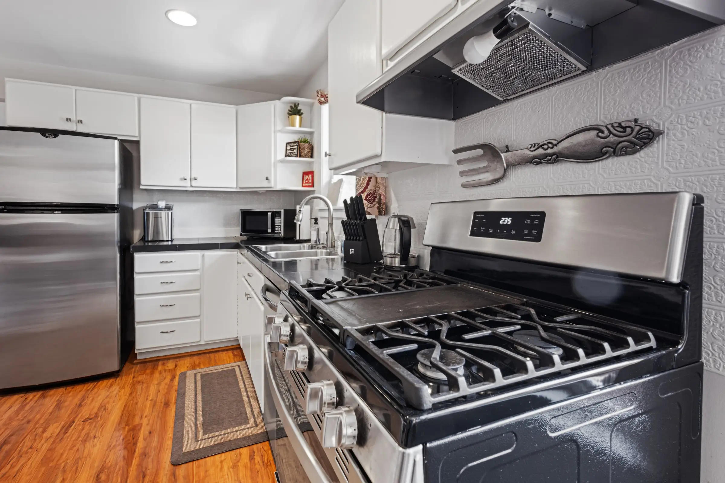 Gas range and fully equipped kitchen with white cabinets at Magnolia House vacation rental, Bend